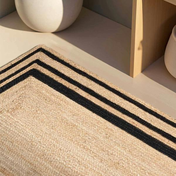 Close-up of a woven rug with black stripes on a neutral background