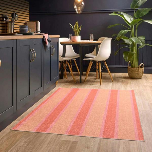 Kitchen with a striped rug on the floor, dining table, and chairs.