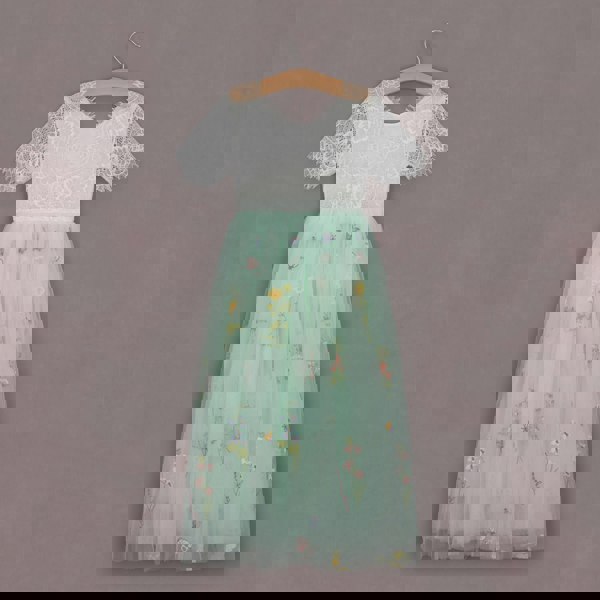 Two-tone dress with lace top and floral skirt on a hanger against a gray background