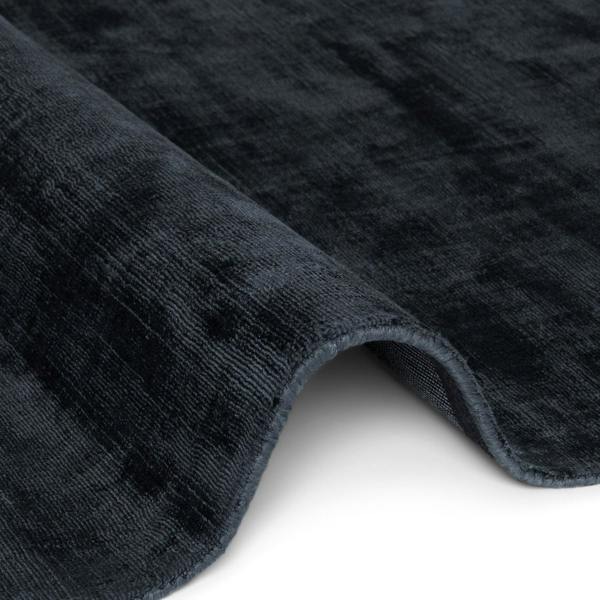 Close-up of a textured dark gray rug corner on a white background