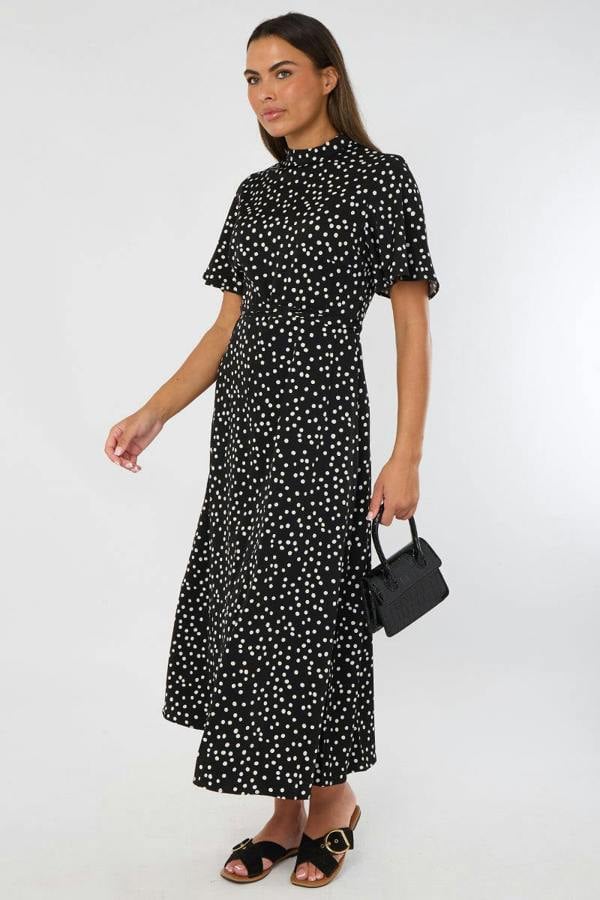 Woman wearing a black dress with white patterns on a white background