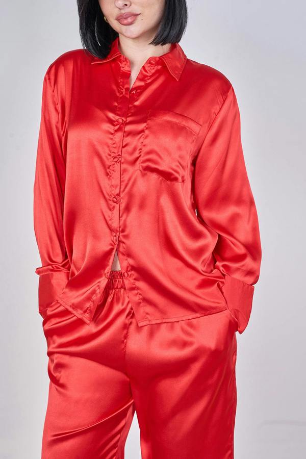 Person wearing a red satin pajama set on a plain background
