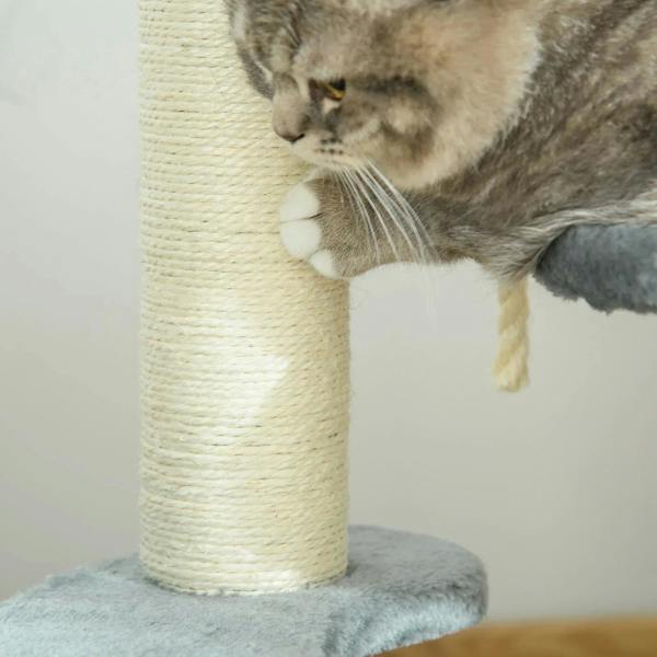 Grey tabby cat reaching on a plush perch beside a sisal-wrapped scratching post