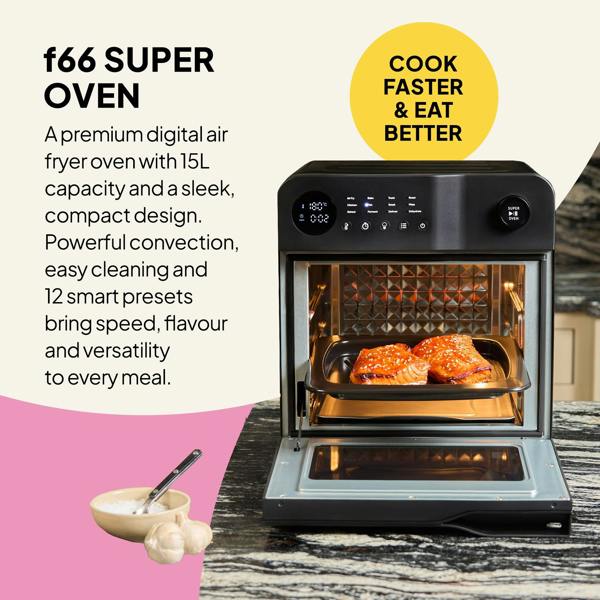 The Fridja f66 Super Oven - 15L Digital Air Fryer Oven in black is open on a kitchen counter, cooking two pieces of salmon. Its display and controls highlight convection features. Nearby sits a bowl of garlic and a spoon.