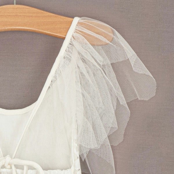 White tulle skirt on a wooden hanger against a gray background