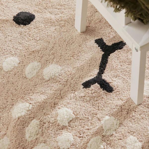 Close-up of a textured beige carpet with black and white patterns