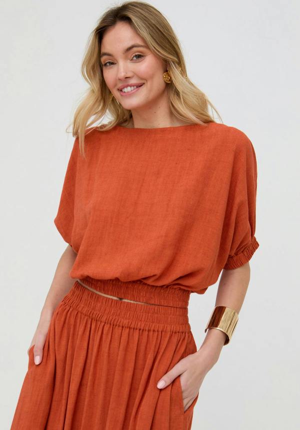 Woman wearing a rust-colored outfit against a white background