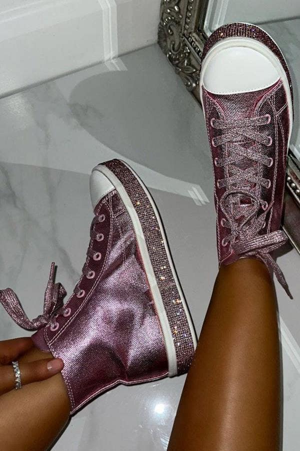 Pink glittery high-top sneakers being worn against a mirror on a marble floor.