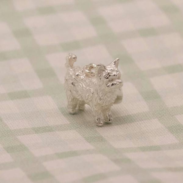 Silver dog-shaped charm on a checkered surface