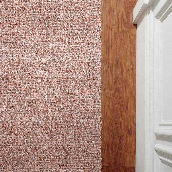 Close-up of a carpeted floor transitioning to a wooden floor with a white baseboard.