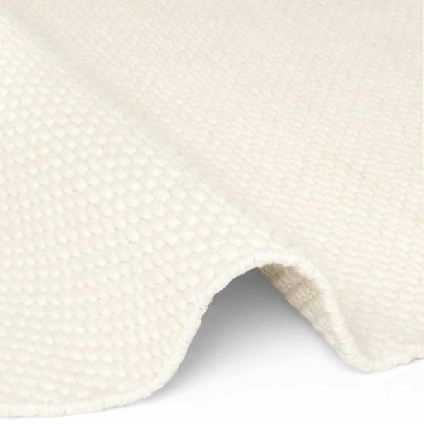 Close-up of a textured white fabric with a slight wave pattern on a white background