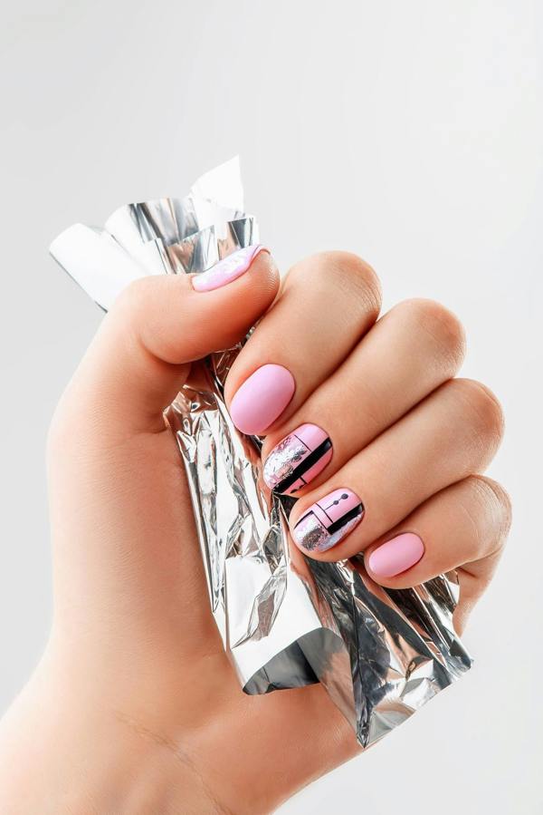 ladies hand holding nail foil showing manicure with nail art designs on each nail 