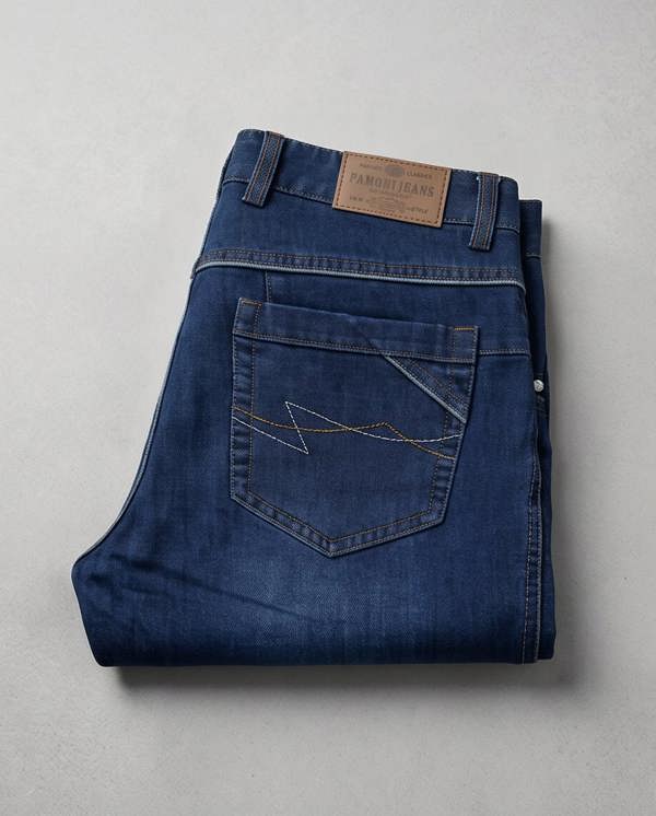 Folded blue jeans with a brand label on a light gray background
