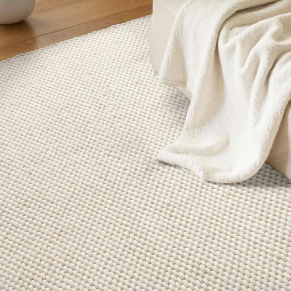 Close-up of a textured beige rug with a white towel draped over it.
