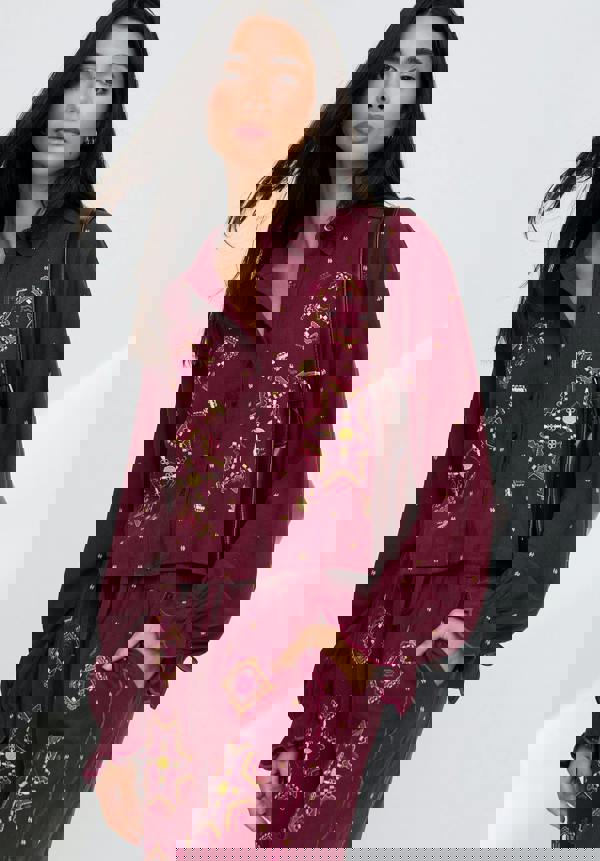 Woman wearing a burgundy outfit with gold patterns on a white background