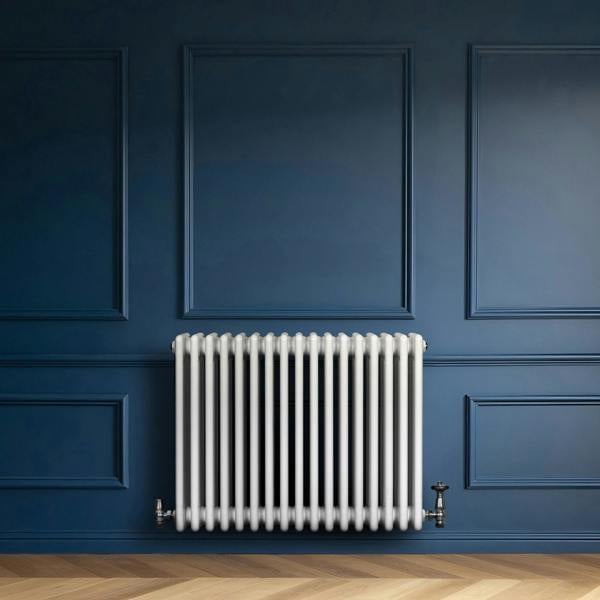 Traditional white 4 column radiator with valves, mounted against a deep blue wall, featuring a sleek, modern design and smooth texture