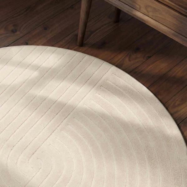 Round beige rug on a wooden floor