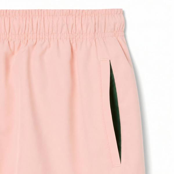 Lacoste pink quick-dry swim shorts with elastic waistband and green pocket lining.