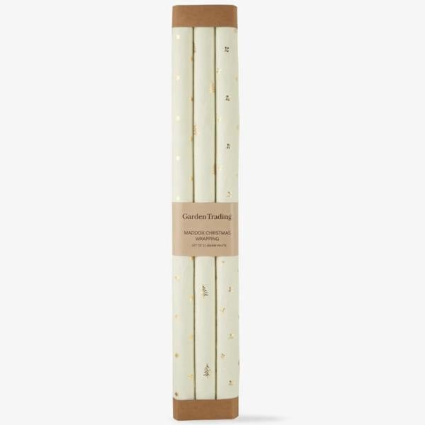 Set of 3 rolls of warm white recycled cotton Christmas wrapping paper with gold foil stars, trees, and berries.