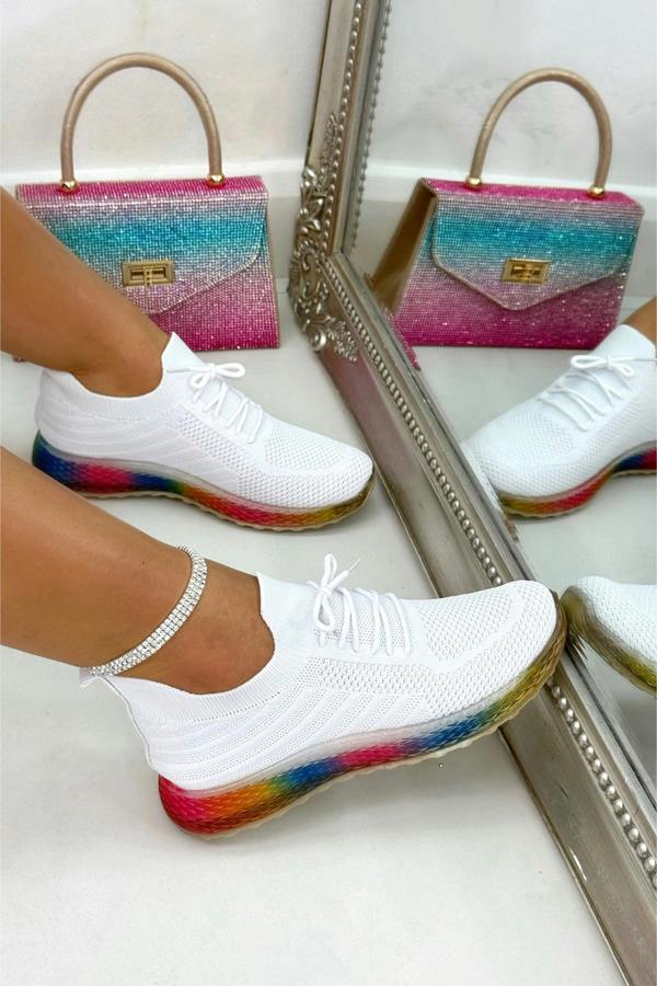 White sneakers with colorful soles worn by a person, standing in front of a mirror.