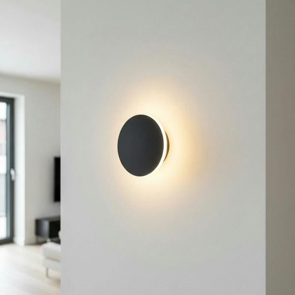 round modern black wall sconce mounted on the wall in a home
