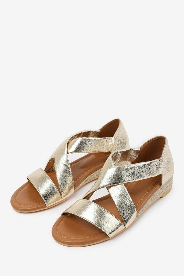 Where's That From Hummingbird Wide Fit Low Wedge Shoes With Cross Over Strap in Gold Metallic