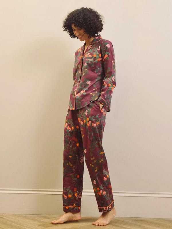 Woman wearing a burgundy floral pyjama set against a plain background