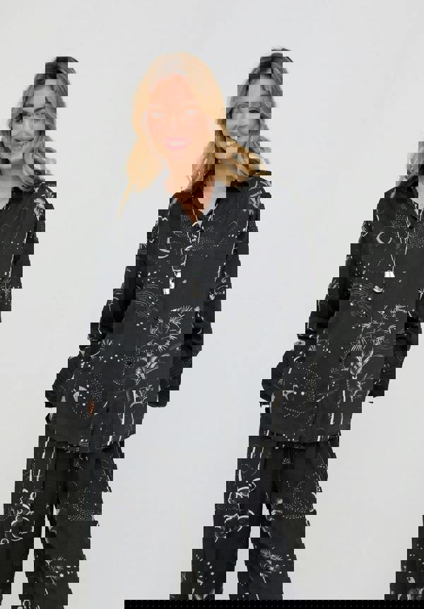 Woman wearing a black patterned outfit on a plain background