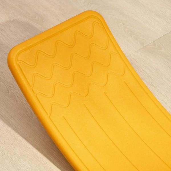 Orange balance board top surface with raised wave grip pattern, close-up
