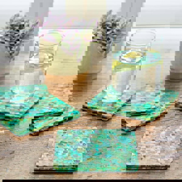 Four green plastic coasters on a table next to a glass of water.