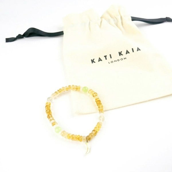Kati Kaia citrine crystal bracelet with yellow and clear beads next to a branded drawstring pouch