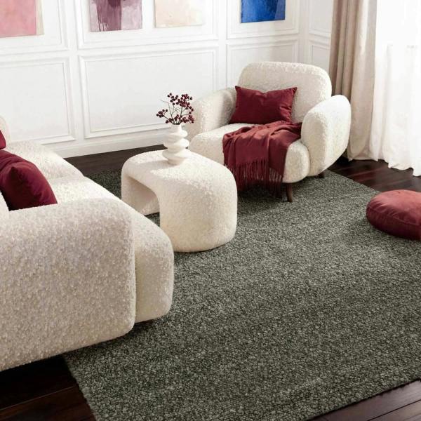 Modern living room with white armchairs, a gray rug, and decorative pillows.