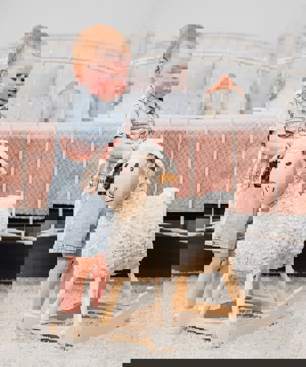 Little girl next to lambert baby rocking animal in pink nursery