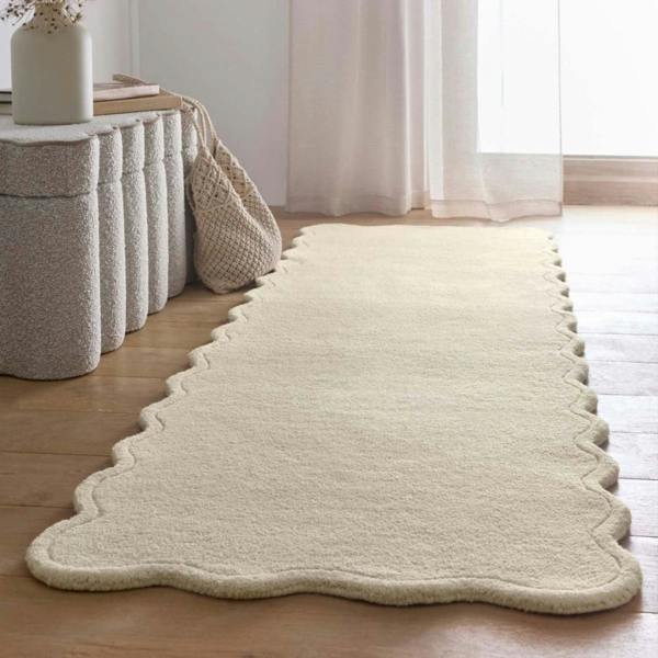 Beige rug on a wooden floor with a white curtain in the background