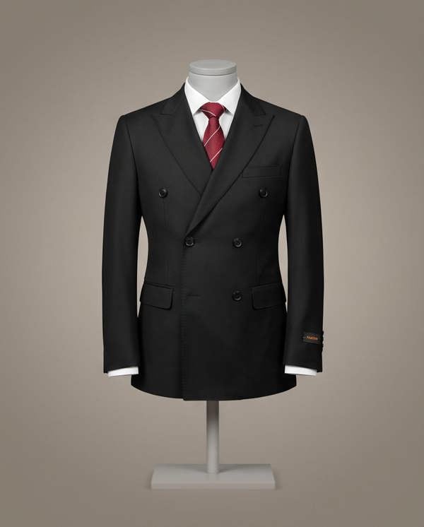 A black double-breasted suit jacket displayed on a mannequin torso with a white dress shirt and a red striped tie, set against a solid warm gray background.