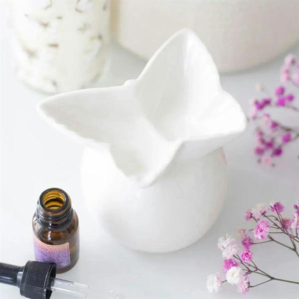 White butterfly oil burner with oil bottle and dropper beside it