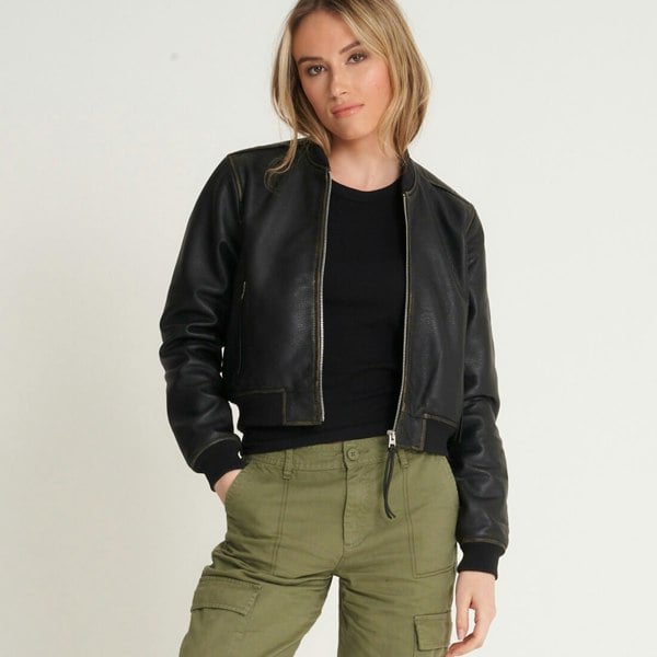 Image shows a model wearing a washed leather bomber jacket over a black tshirt. The jacket is made from real leather and is black in colour. It has a central zipline and the zip has a pully string.