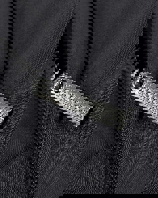Lambretta Mens Padded Hooded Classic Badge Parka, close-up of the metallic zipper pull with 'Lambretta' engraving on black fabric.