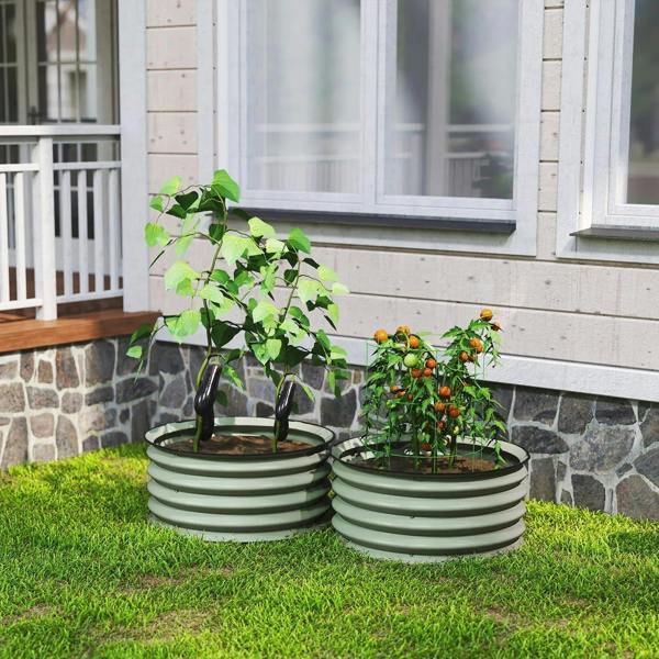Two green ribbed metal planter boxes with leafy plants on grass