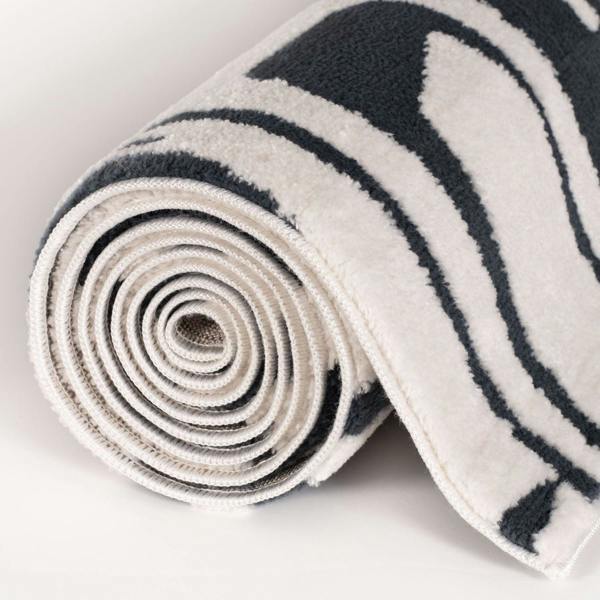 Rolled-up rug with black and white pattern on a light background