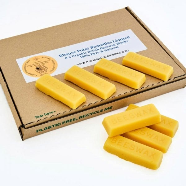 Eight blocks of raw beeswax in a cardboard box, with the box having a label indicating '100% Pure Natural Organic British Beeswax' and the brand 'Rhoose Point Remedies Ltd.'.