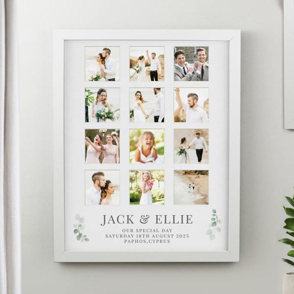 A large white 12-aperture collage photo frame by Abode Home & Gifts hanging on a wall, showcasing full-colour destination beach wedding photos. The bottom mount includes green eucalyptus leaves and printed text reading "JACK & ELLIE OUR SPECIAL DAY SATURDAY 18TH AUGUST 2025 PAPHOS, CYPRUS".