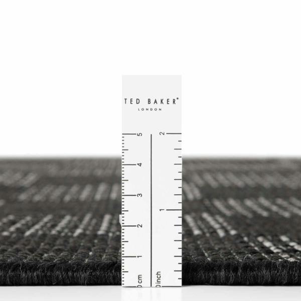 Black textured rug with a ruler for scale on a white background, featuring the Ted Baker London brand.