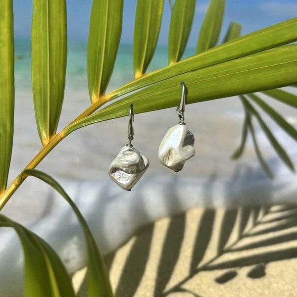 Stunning silver shell hook earrings by LENAE London, shot on an exotic beach.