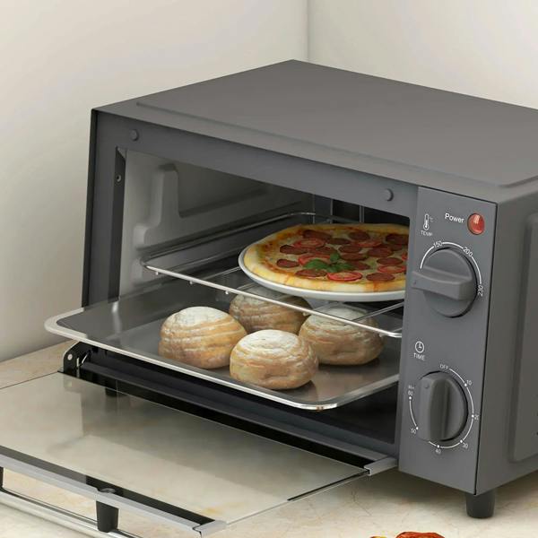 Grey countertop mini oven with open door, wire rack holding pizza and rolls.