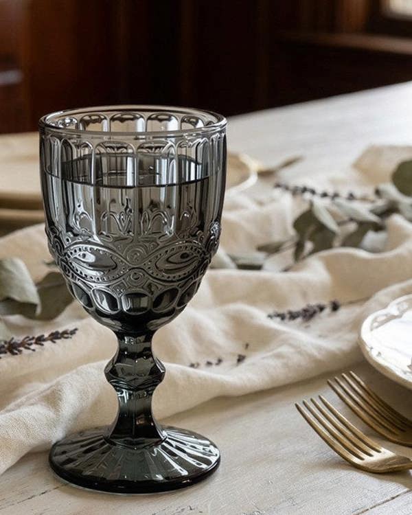 Decorative glass goblet on a table with a floral tablecloth and silverware.