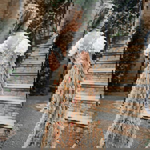 Young girl in a floral dress standing outdoors with a building and steps in the background