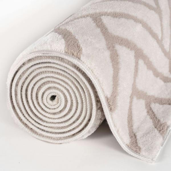 Rolled-up beige and brown patterned rug on a light gray background