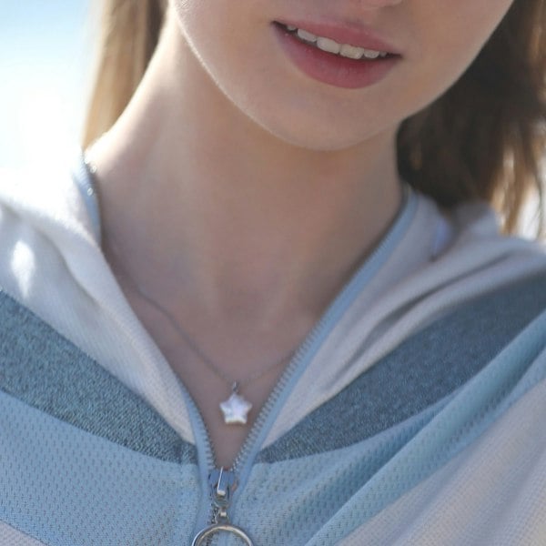 A close up of star shaped pendant necklace on a model.