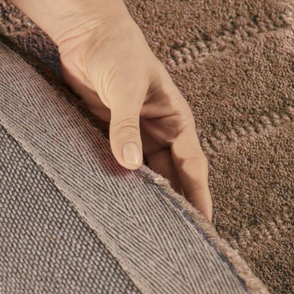 Hand touching the edge of a carpet border